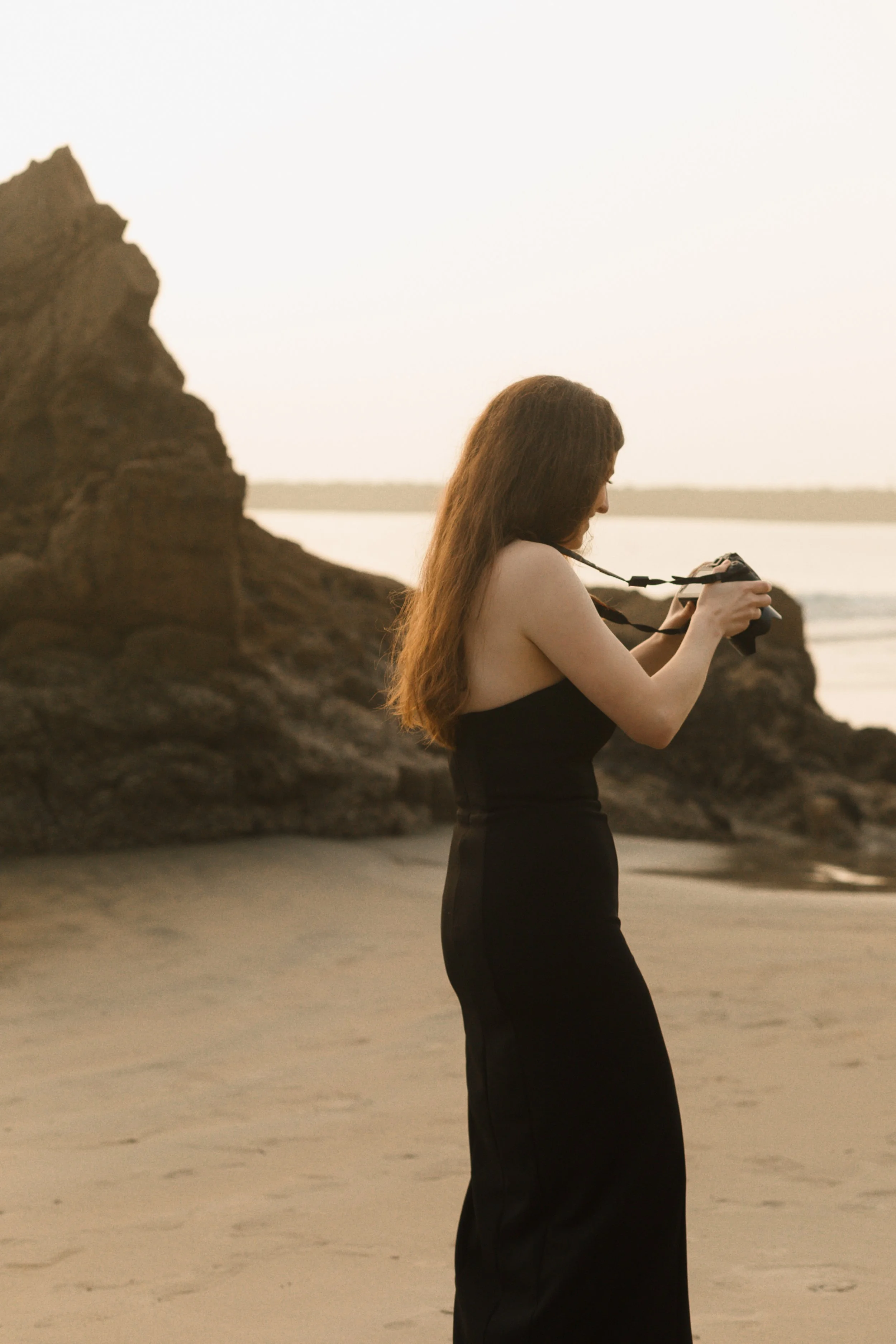girl holding camera on the beach sunset during proposal in newport beach