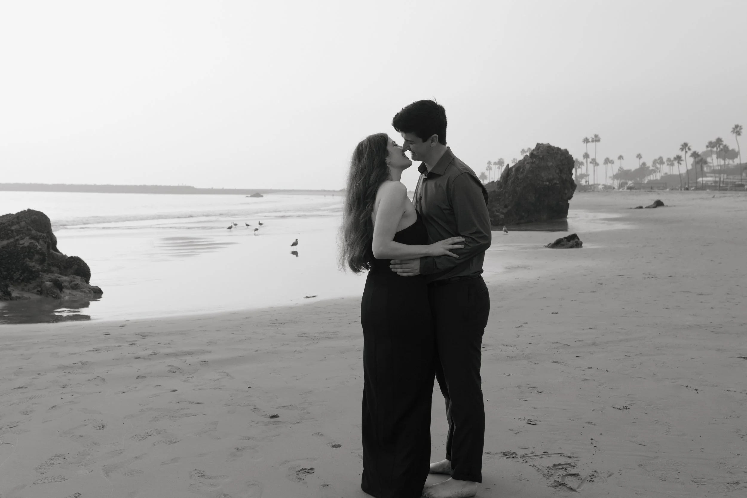 black and white photo of couple going in for a kiss on the beach in newport during their proposal