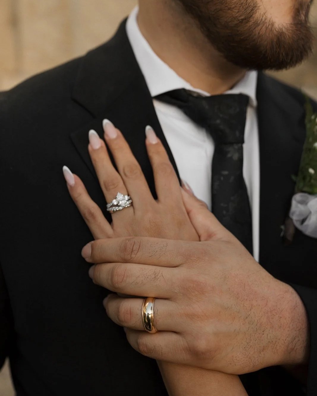 detail photo of groom's chest showcasiing his chin and below of jacket with his hand on his chest holding his brides hand showcasing their wedding rings at the santa barbara courthouse