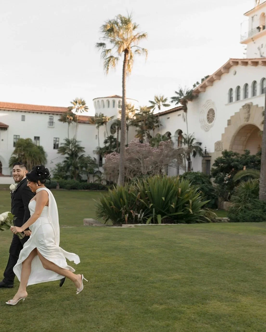 Artsy candid of couple running across the grass in the gardens at the Santa Barbara Courthouse Sunken Gardens, capturing motion and joy in a playful elopement moment