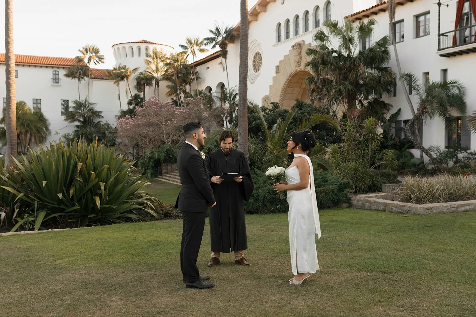 Couple standing face to face with officiant during elopement ceremony inside the Santa Barbara Courthouse Sunken Gardens, exchanging vows in an intimate wedding ceremony