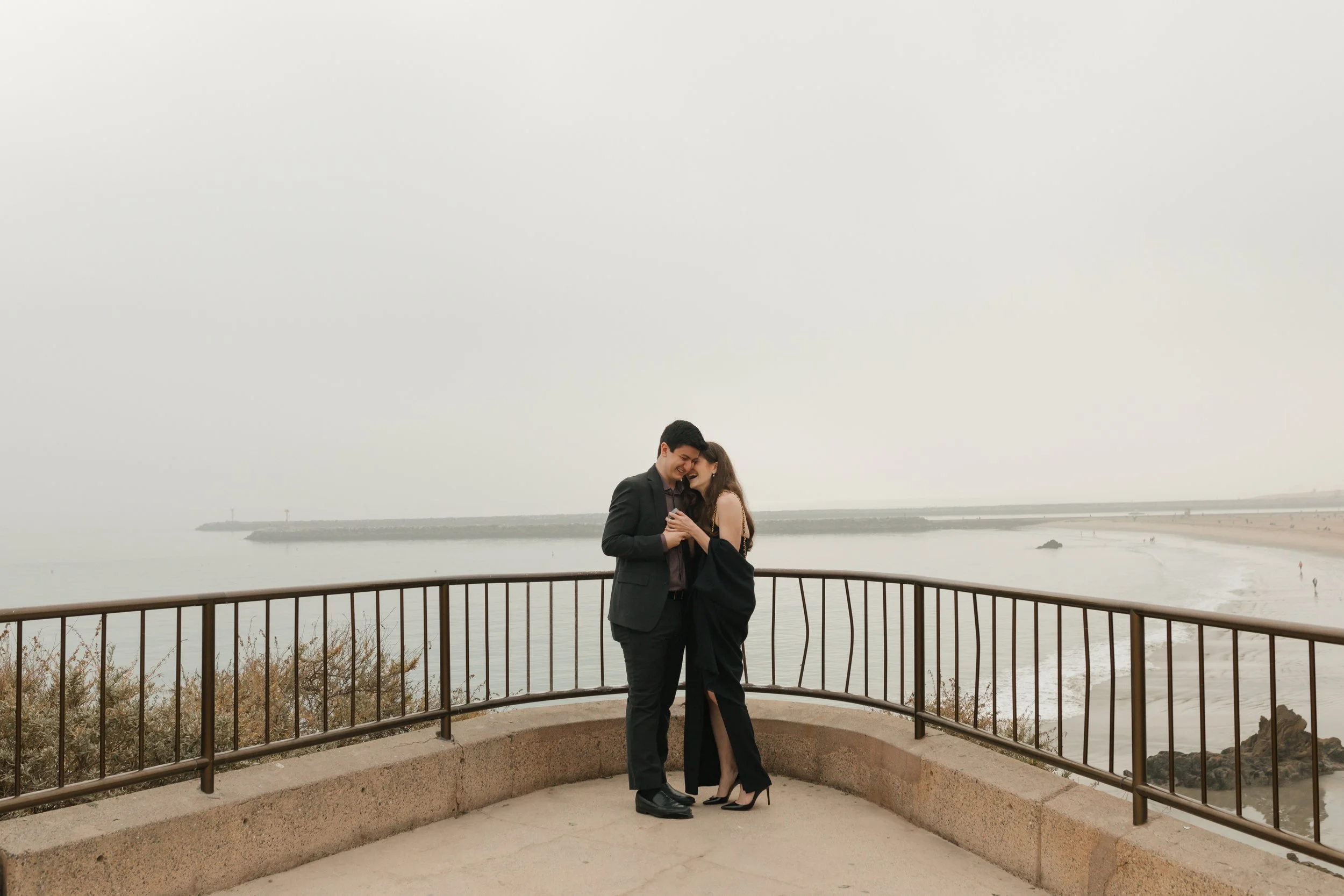 couple hugging after proposal  at lookout in newport beach with the ocean in background