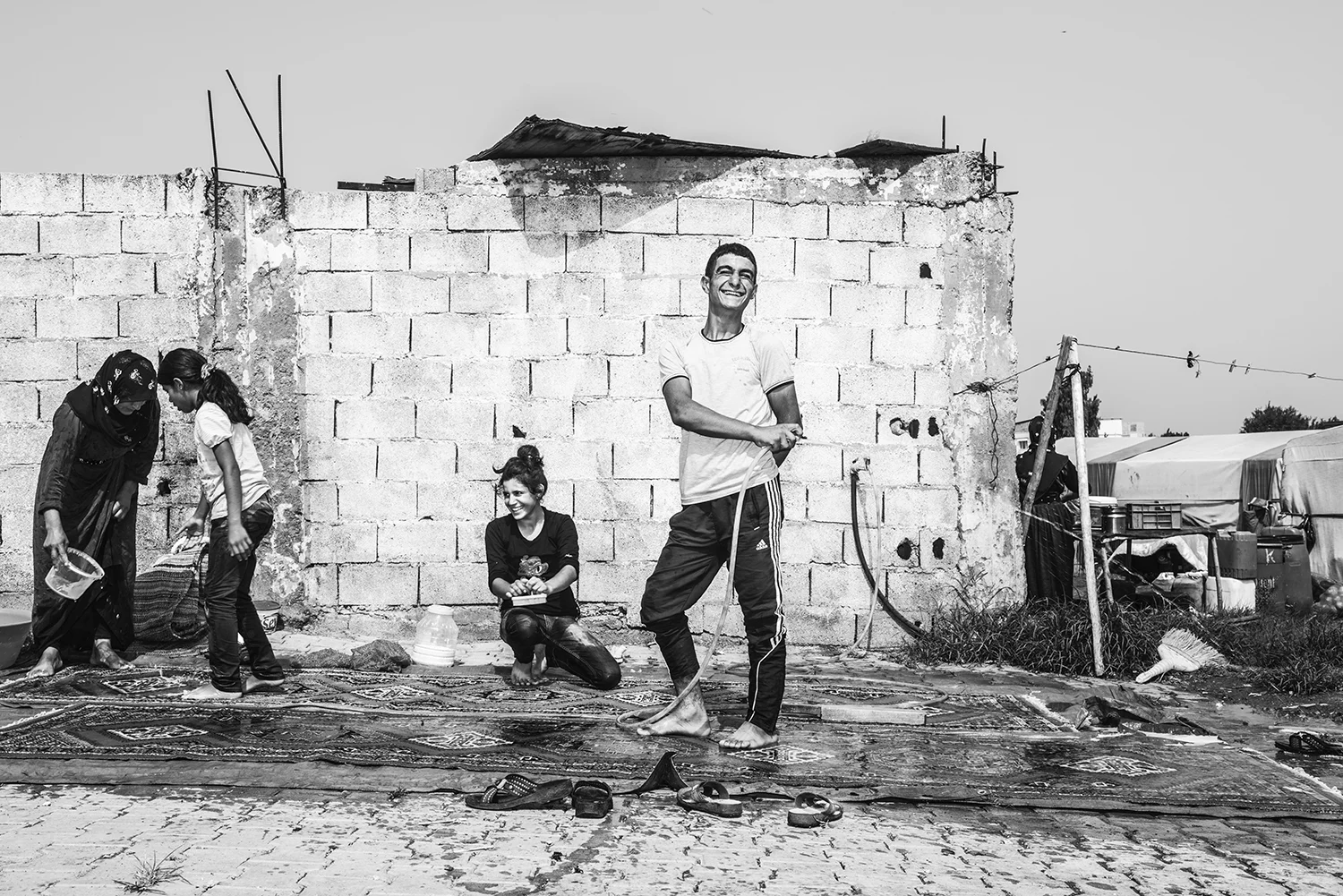 a Kurdish family wash floor carpet for their tent house as a part of preparation for Muslim holiday Eid al fitr in informal refugee camp. Southern Turkey, 2015 ©Go Nakamura photography