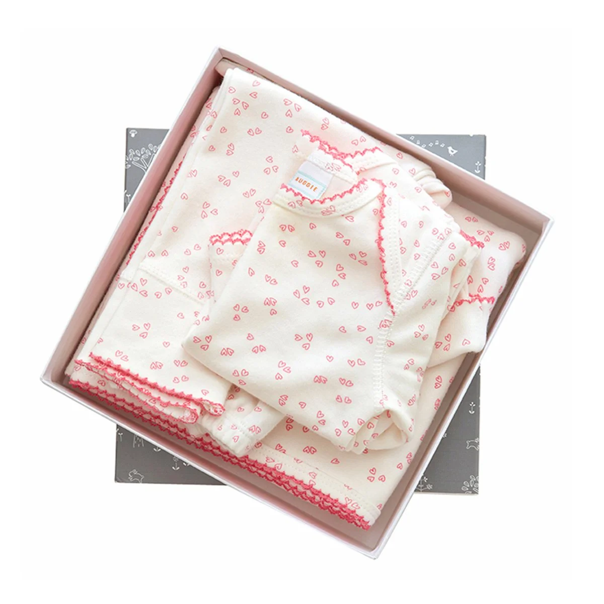 An organic cotton layette with a pink heart pattern and pink stitching made by Little Auggie.