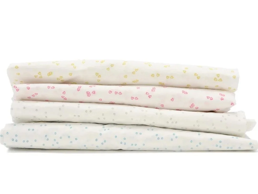 Little Auggie crib sheets with small heart and dot patterns in yellow, pink, grey, and blue, stacked horizontally.