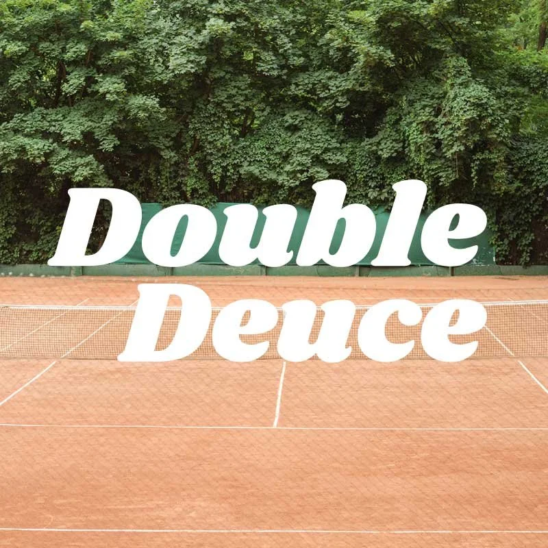 Text on tennis court reads "Double Deuce," with a green backboard and trees in the background.