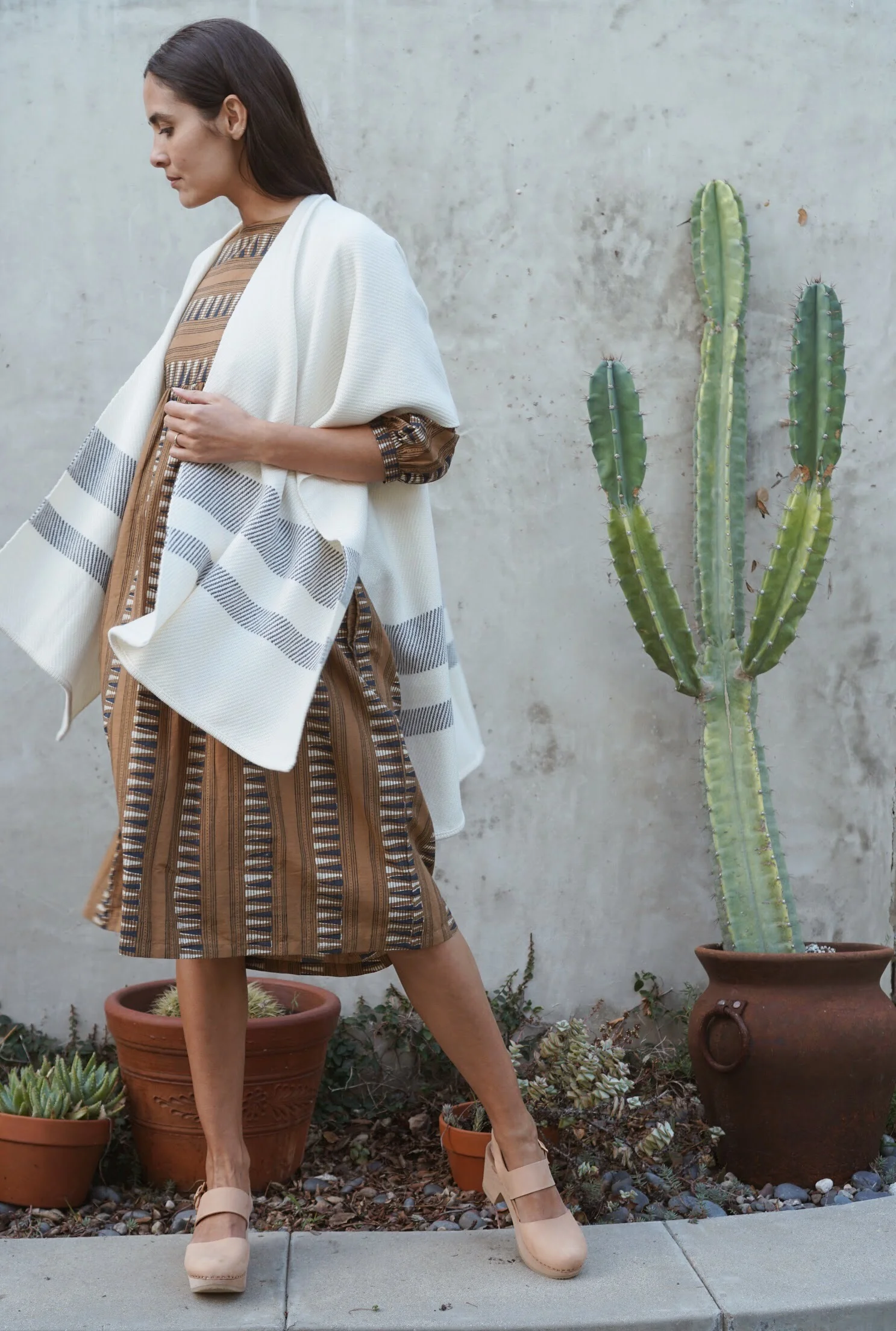Kopal Kuku Dress in Mustard Strip + Maiyet Stripe Hem Poncho in Ivory + Zuzii Closed Toe Clogs in Natural.