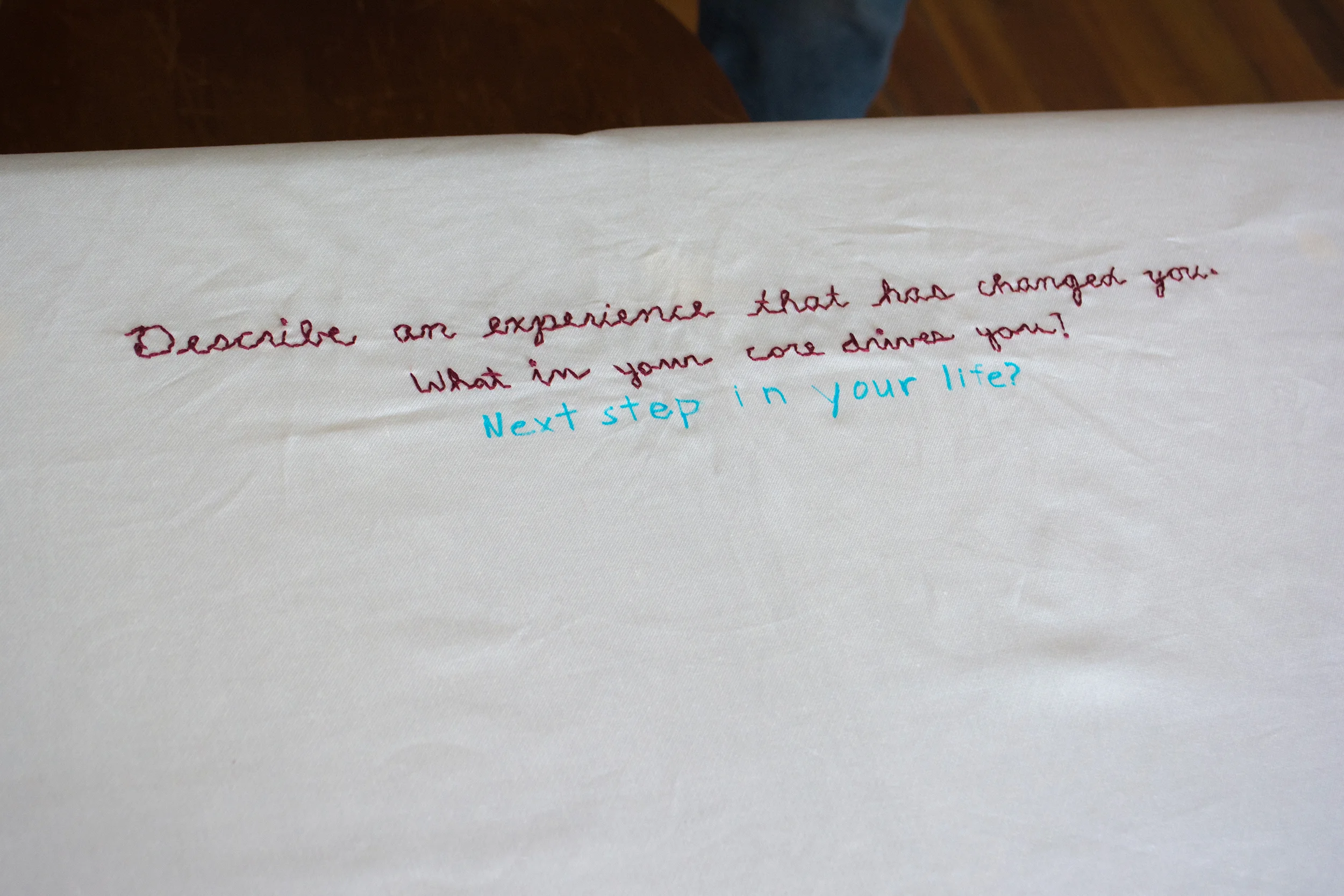 The first conversation began with "Describe an experience that has changed you" and ended at "What in your core drives you?" The second conversation began with that and ended with "Next steps in your life?" This will be embroidered into the tablecloth before the next participants resume the conversation. They will share a beverage out of the same mugs.