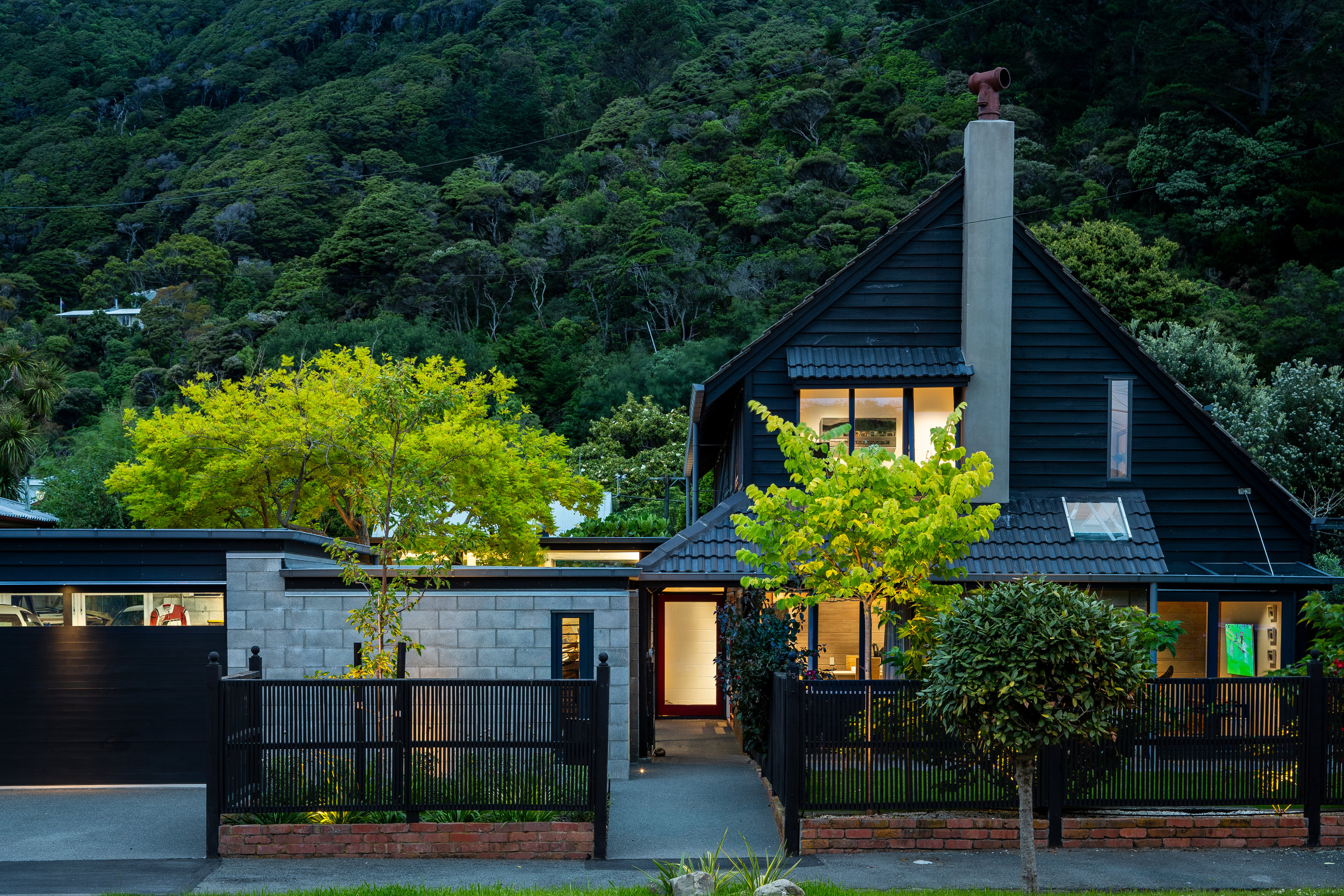 The project involved the renovation of an existing 2 level house and garage originally designed in 1979 by Gordon Moller, to better facilitate their lives with a disabled adult daughter. It included a new/ relocated kitchen and scullery with improved visual and physical access to the family room. An extended family room with improved access to the garden, improved access to the front garden from the living room and an overall upgrade to doors and windows, services and finishes. The extension of the garage to accommodate a disability vehicle with an additional workroom and wood store. The house sits on a flat section with a garage towards the street frontage linked to the house via a verandah. Living facilities are on the ground floor with the bedrooms located at the top level. Both the house and garage have a distinct architectural character typical of Gordon Moller’s 1970s work, with a steeply pitched roof, stained weatherboards and exposed concrete block walls. The design solution involved the demolition of a smaller study annex, also designed by Craig Craig and Moller in 1991. This annex was underutilized but was built over a subterranean wine cellar the family wished to keep access to. Hence the kitchen/ scullery were relocated into a new pavilion of a similar footprint, but large enough to accommodate easy movement for wheelchair and a mattress on the floor. The walls to the existing kitchen and family room were removed and a new glazed roof link was installed between the pavilion and the main house introducing light into the centre of the space. A reflection pool was also installed adjacent to the kitchen and entry.