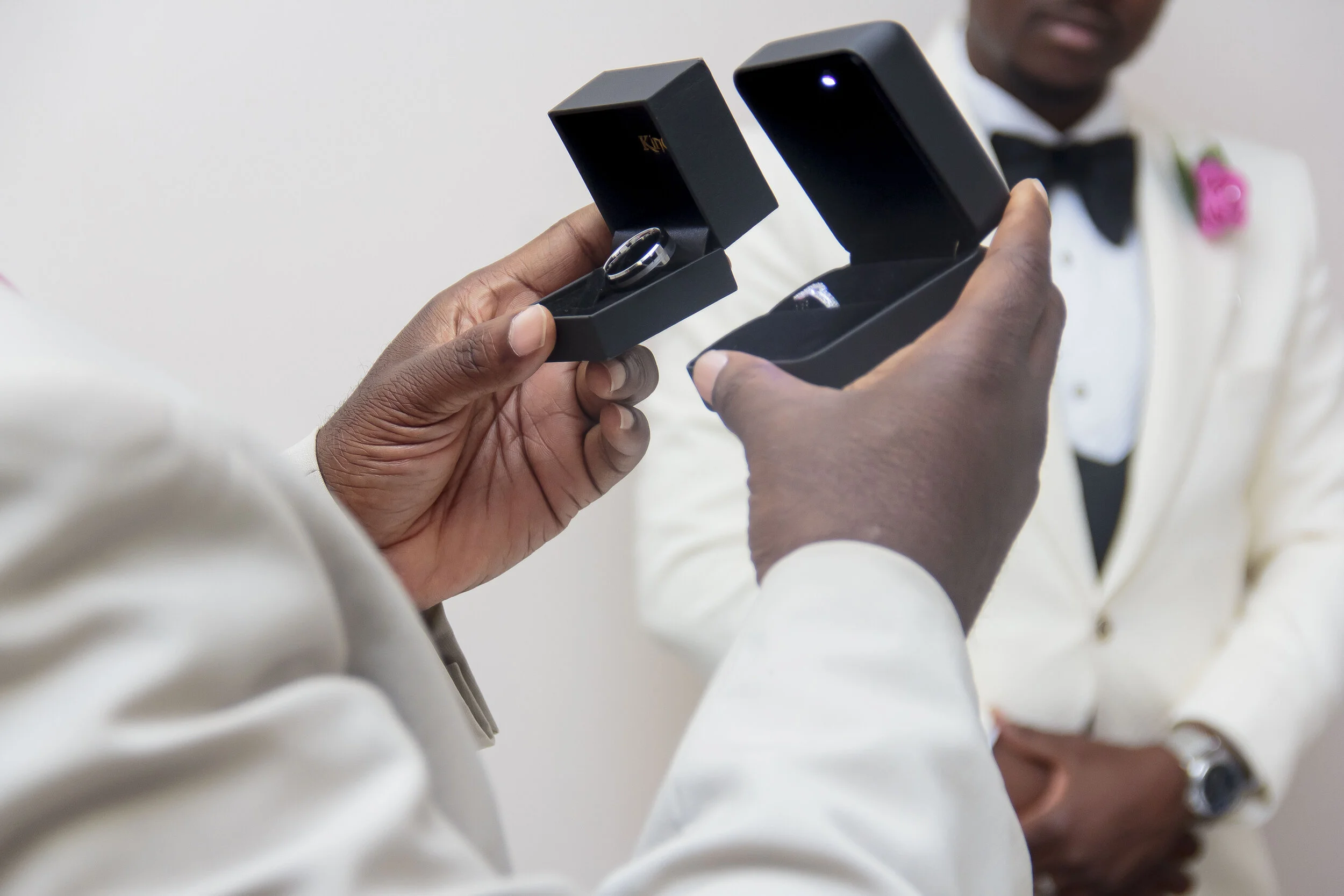 A person holding an open black ring box with a ring inside.