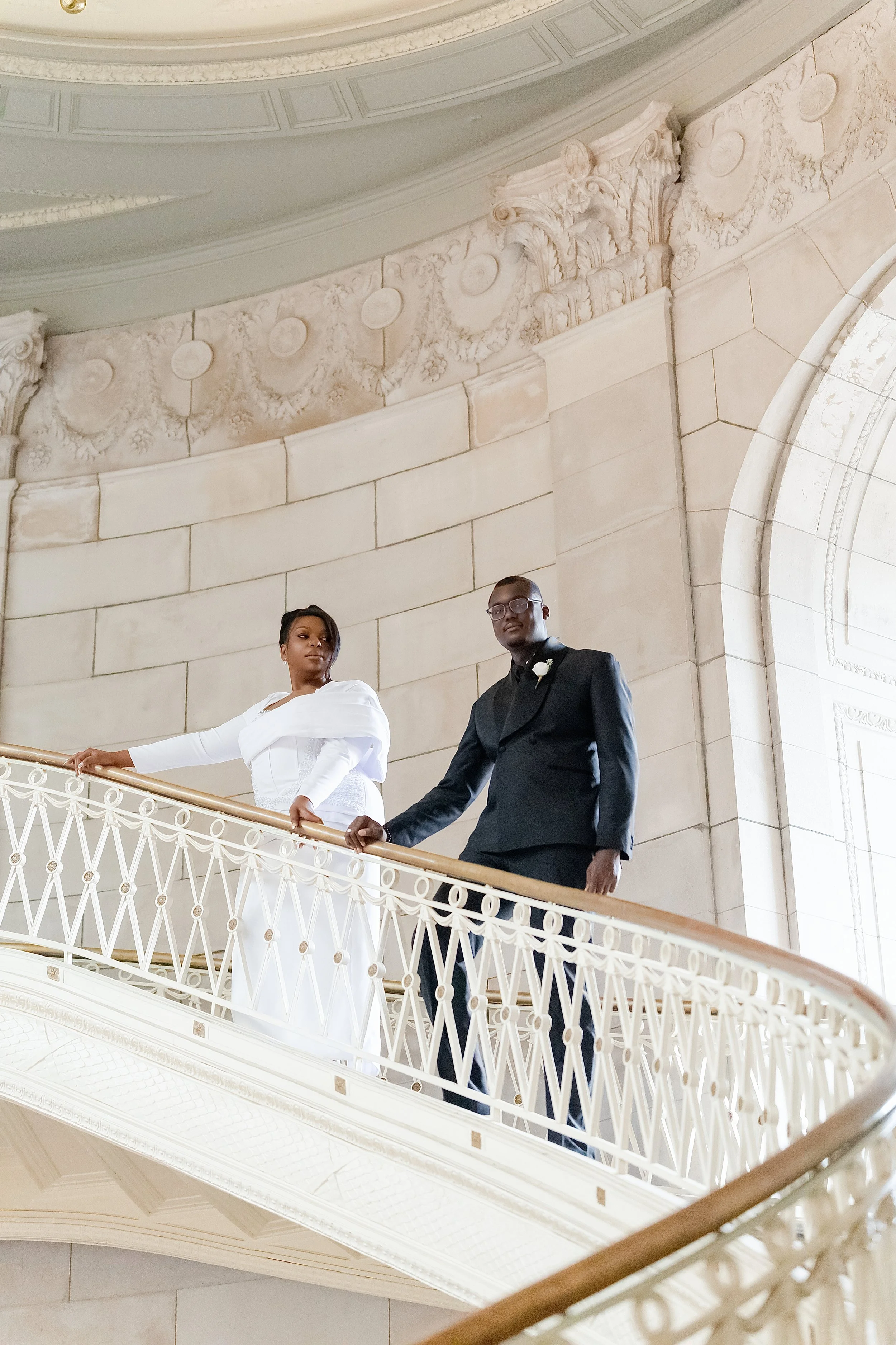 Bride and groom standing on an ornate balcony during their wedding portrait session