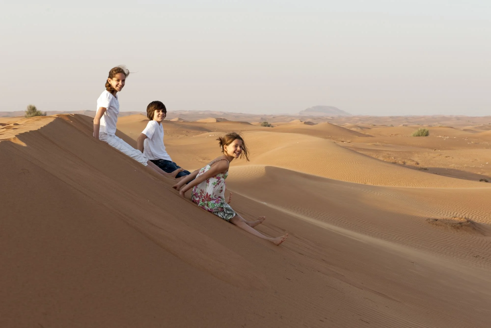 children-sitting-on-sand-dune-dubai.jpg