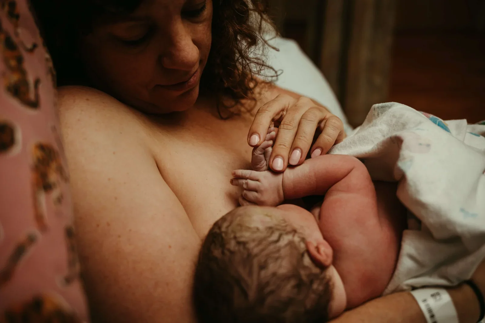 Portland baby photographer captures mother with newborn baby touching hands in a hospital bed