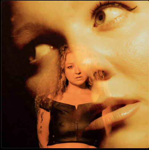 A woman and a large projected image of a woman's face with eyes and lips close-up.