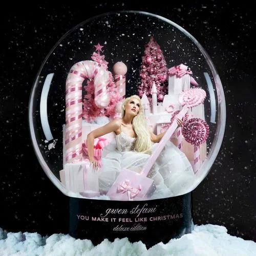 A snow globe featuring a blonde woman in a white dress surrounded by pink Christmas decorations, including candy canes, Christmas trees, and wrapped presents.