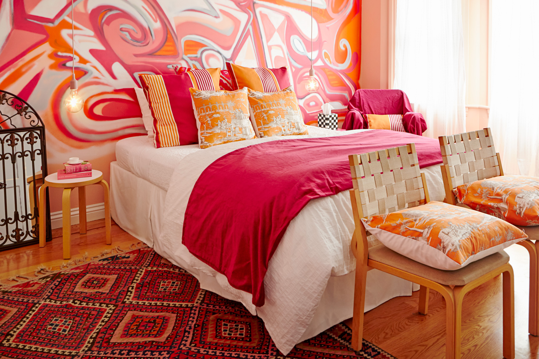 This colorful bedroom owes its color scheme to a Ken Done print. The room combines a graffiti mural by local artist Nicolas Held; toile, ikat, and striped fabric, and antique rug for an eclectic playful vibe. 