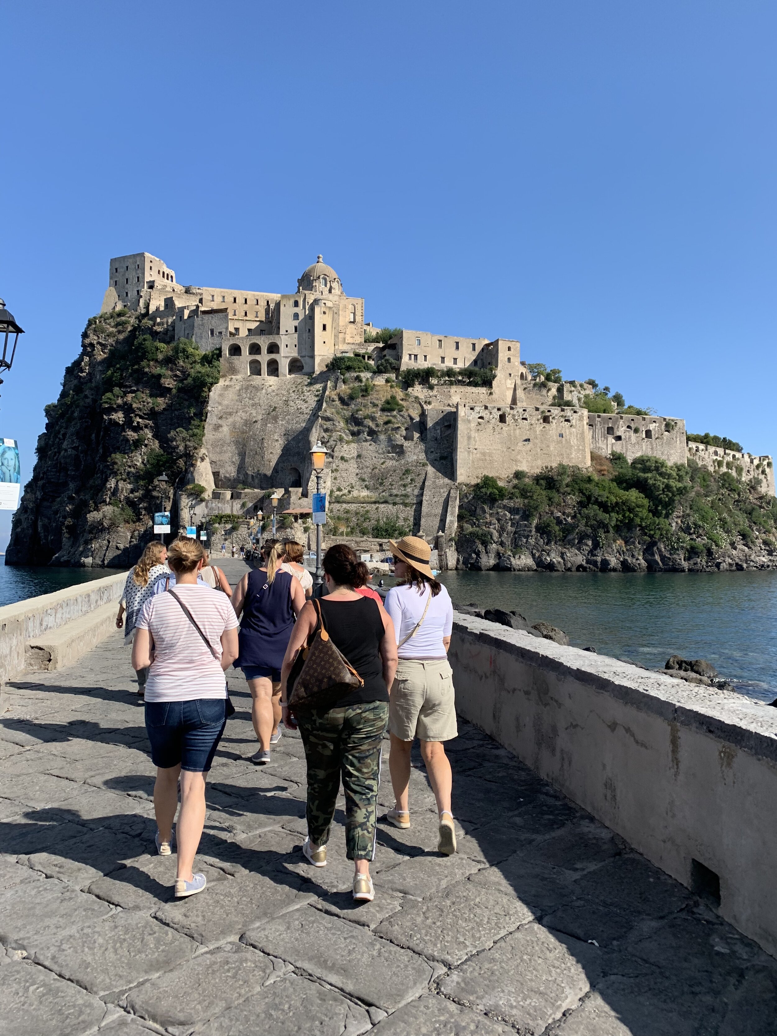 Guests walk to Castle Aragonese | EAT.PRAY.MOVE Yoga Retreats | Ischia, Italy