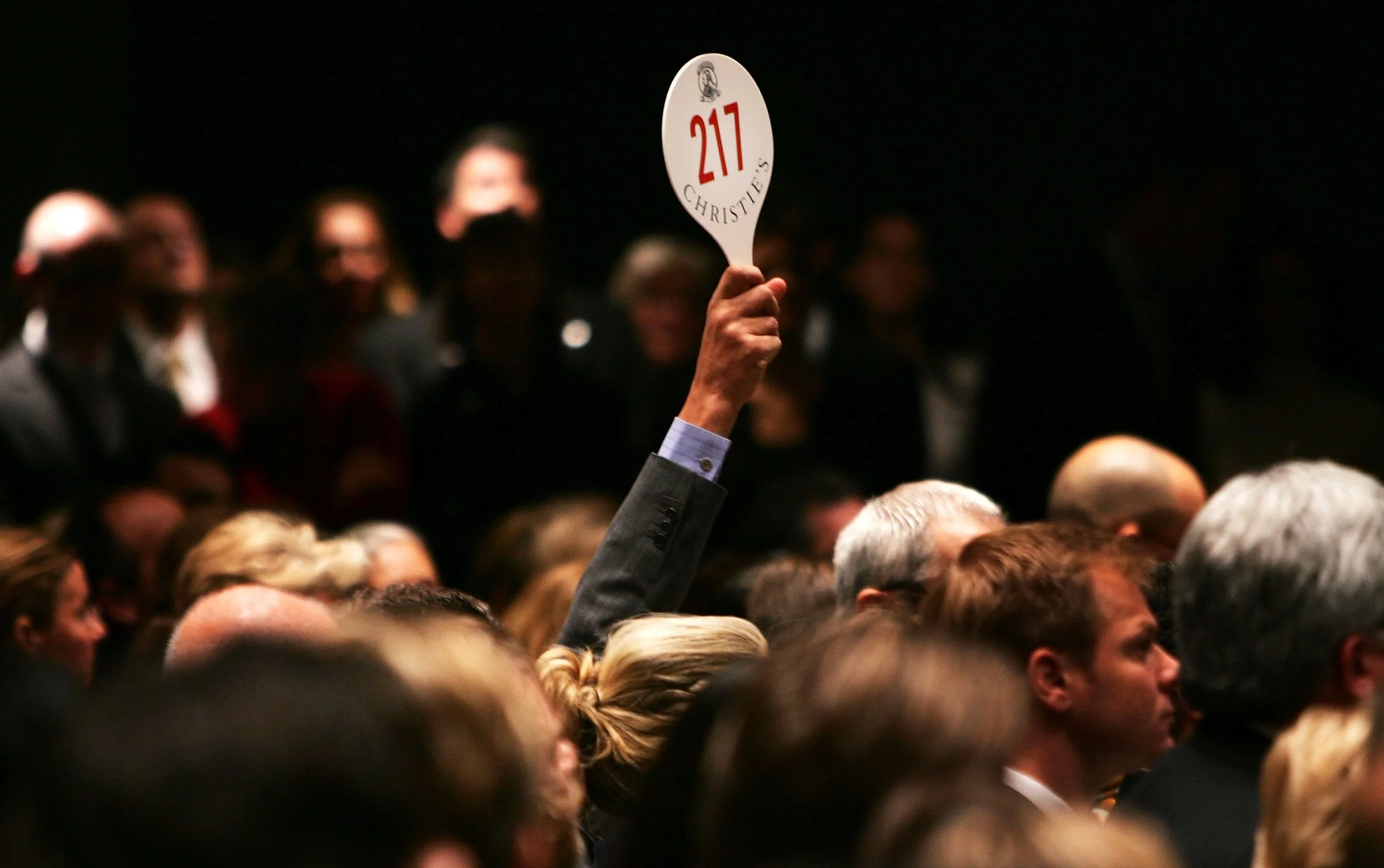 NEW YORK - NOVEMBER 15: A man holds his hand up while bidding on a work of art inside the auction house Christie's during the Post-War and contemporary Art sale November 15, 2006 in New York City. Christie's estimates that works by Warhol, Willem de Kooning, Roy Lichtenstein and others could go for up to $220 million in what the auction house says may be the most valuable post-World War II and contemporary art auction in history. Warhol's 'Mao' portrait from 1972 went for over 17 million, setting an all time record for the artist. (Photo by Spencer Platt/Getty Images)