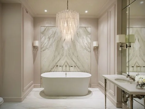 Instantly upgrade your humdrum bathroom into a fabulous bath by adding a statement chandelier. This glass leaf chandelier effortlessly lights up the room! Its delicate details match the all-white opulence of the bathroom. 
#RenoGuide #Bathroom #Chandelier #Lighting #BathroomGoals #BathroomInspo #Design #DesignInspo #InteriorDesign