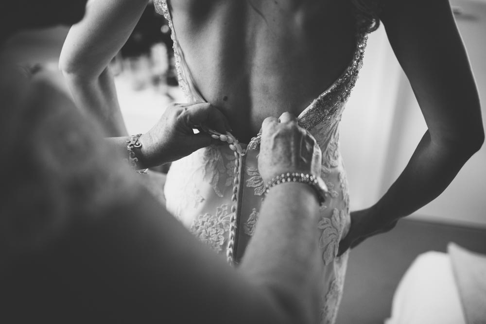 A bridesmaid puts the finishing touches to the wedding Dress | Cardiff Wedding Photographers