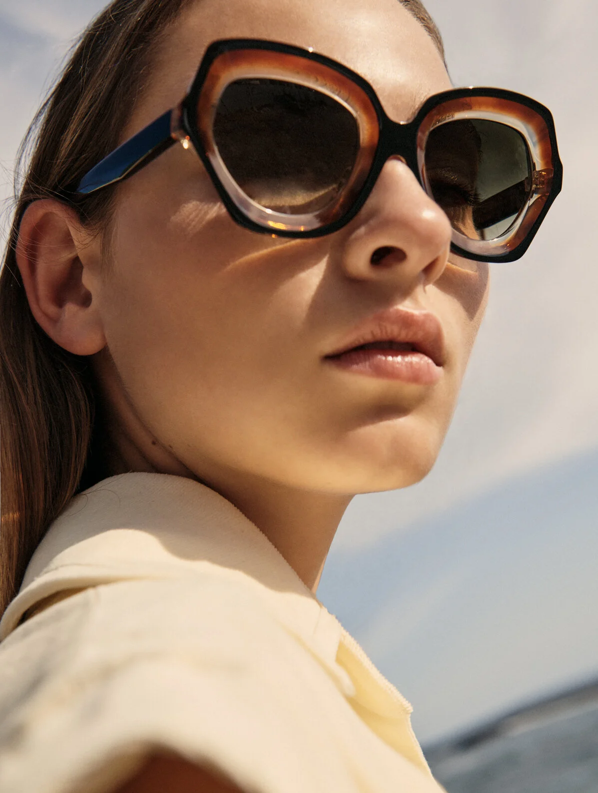 Close-up of a woman wearing large, tortoiseshell sunglasses outside on a sunny day