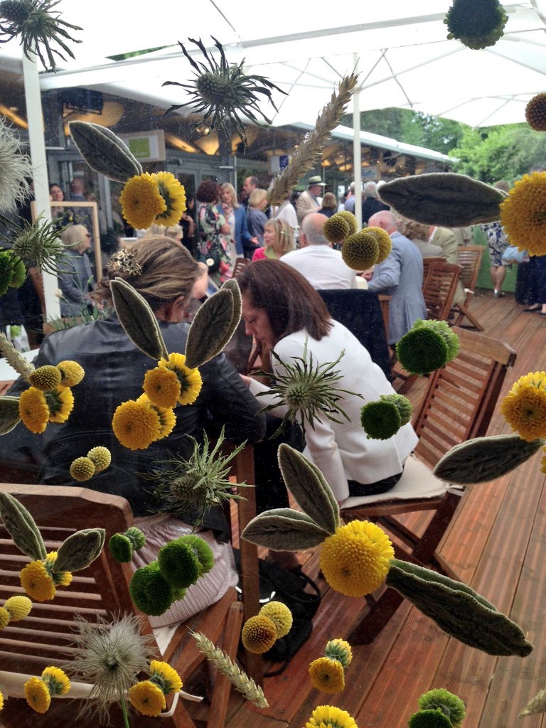 Transparent screens decorated with glued flowers in bright sunny shades of yellow sheltered visitors in the garden bar.