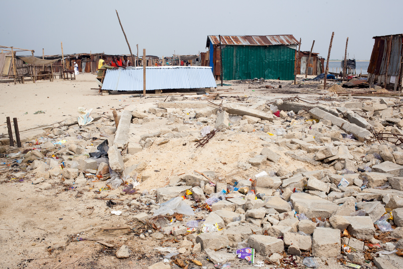  Beyond the rubble of a destroyed home, the roof of a new building is being raised. 