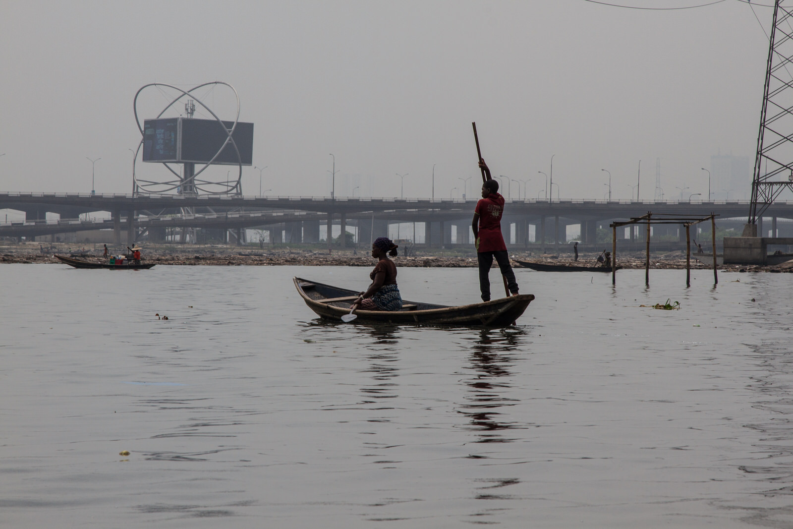  Fishing remains one of the main sources of livelihood for members of the community. Fishermen work in the lagoon with the Third Mainland Bridge in the background - the 2nd longest bridge in Africa. 