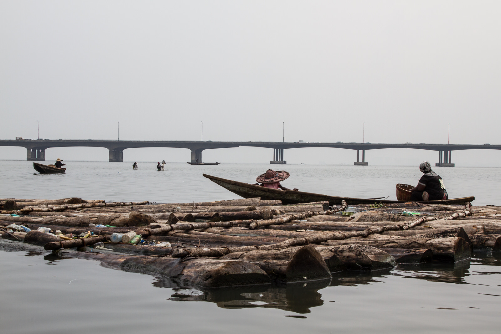  Fishing remains one of the main sources of livelihood for members of the community. Fishermen work in the lagoon with the Third Mainland Bridge in the background - the 2nd longest bridge in Africa. 