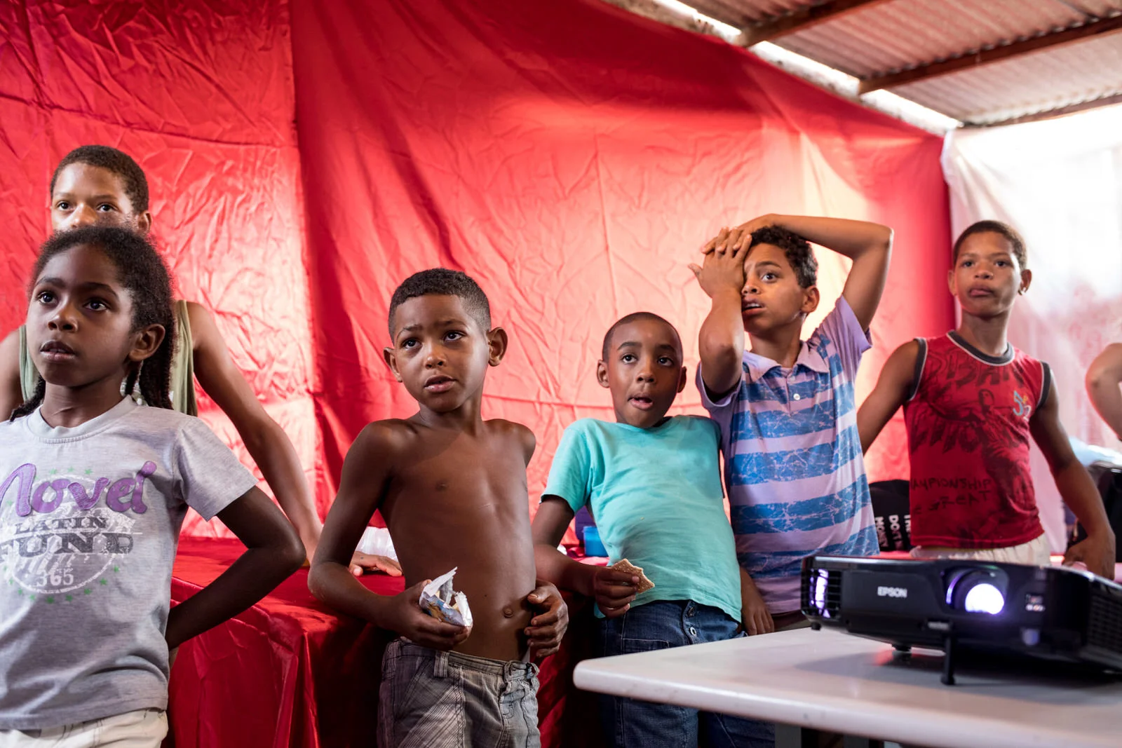 Children watching music videos projected on the walls of the community centre in Ocupação Guerreira Maria.