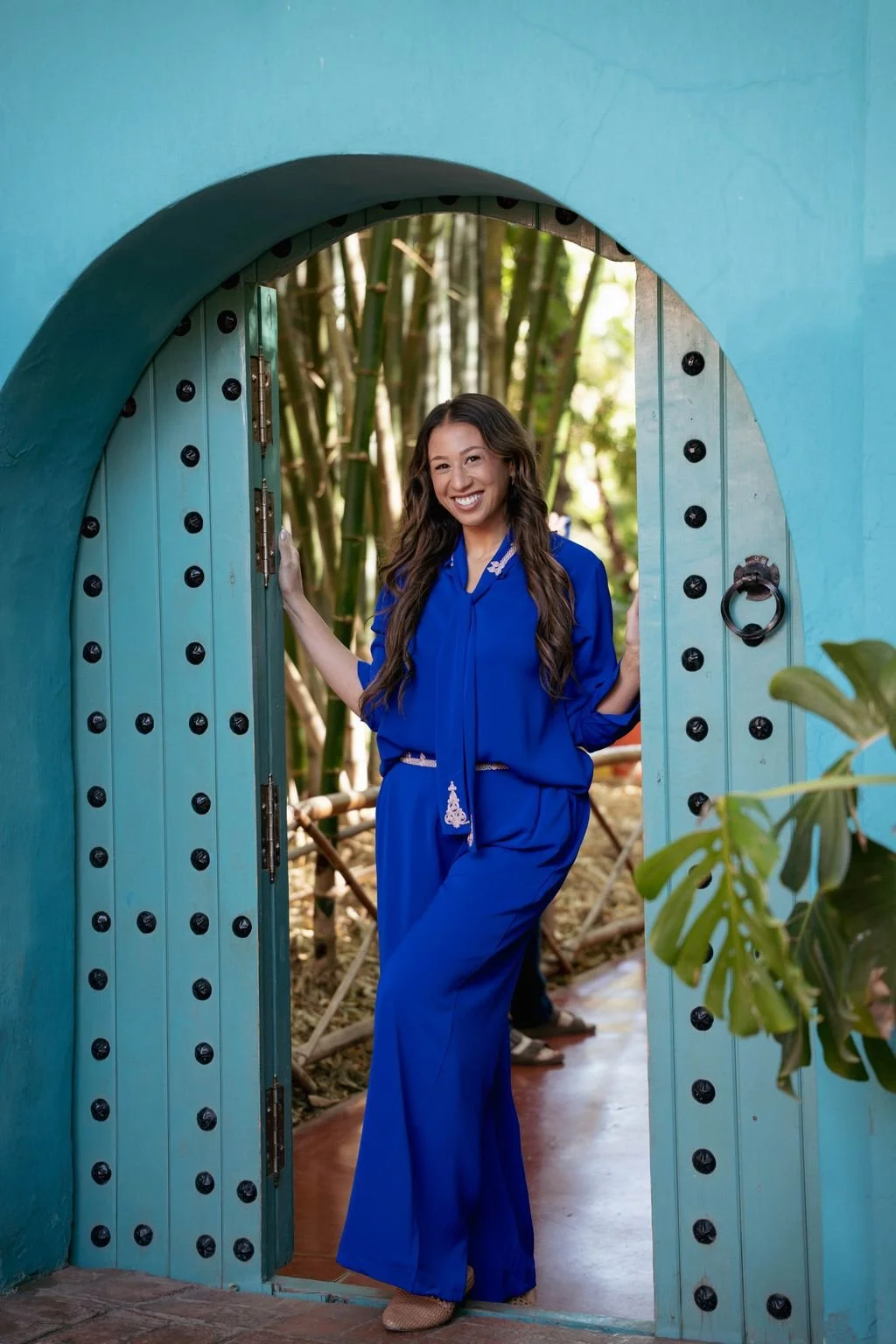 Danielle standing in blue archway wearing traditional Moroccan outfit in their signature blue