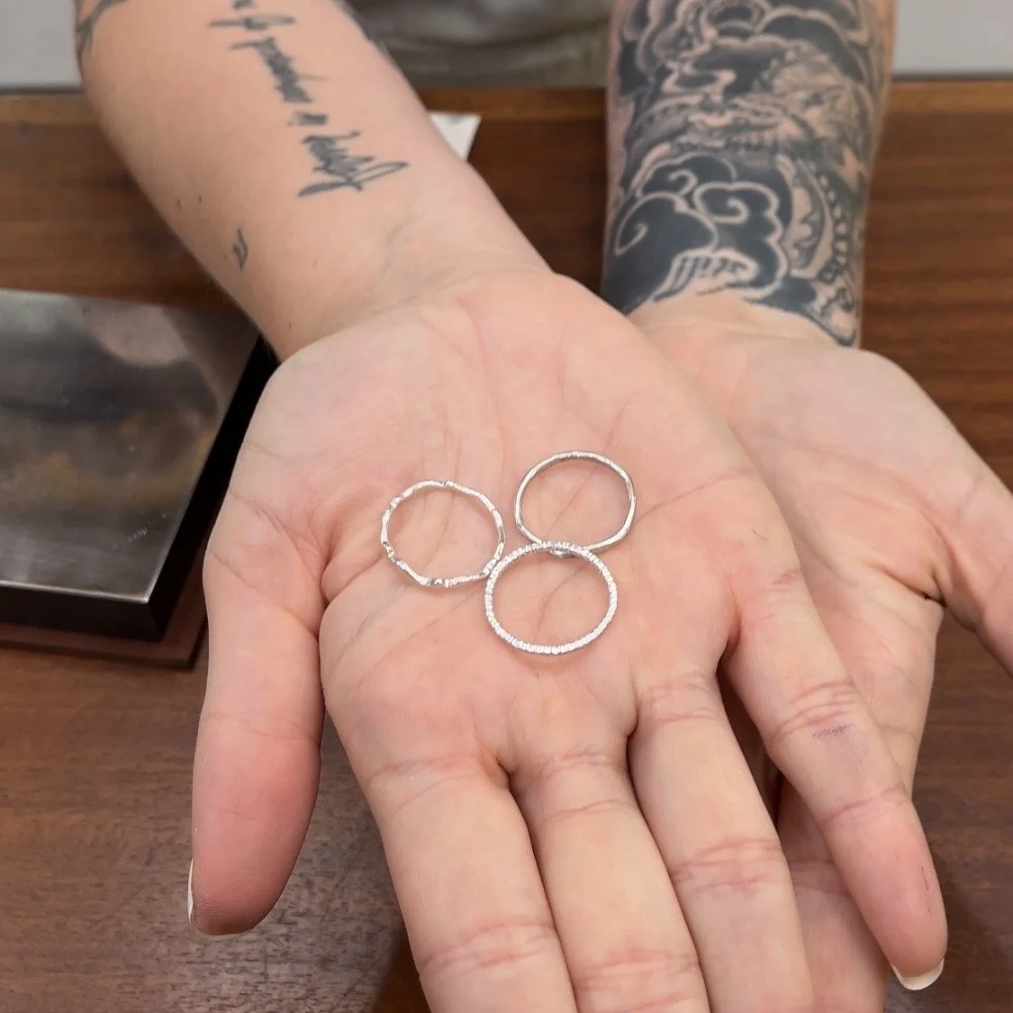 Three unfinished sterling silver stacking rings resting in a student's hand.