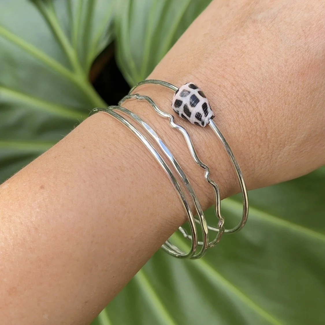 Sterling silver seashell bangles handmade in Hawaiʻi, featuring a hebrew shell and textured silver designs