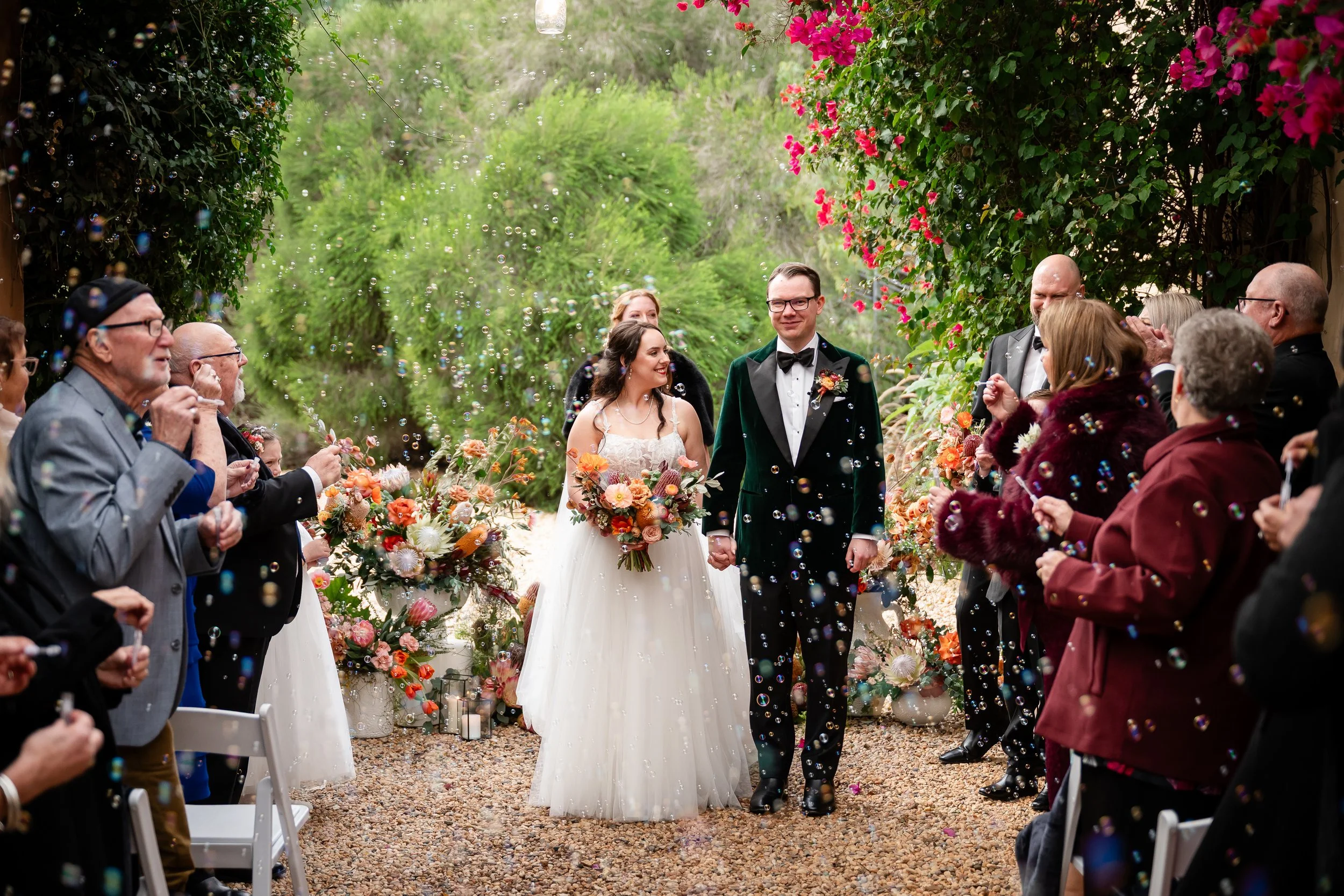 Bride and groom walking through a joyful bubble exit after their outdoor ceremony at Al Ru Farm in the Adelaide Hills, beautifully coordinated by Adelaide wedding planner Sparrow Weddings & Events.