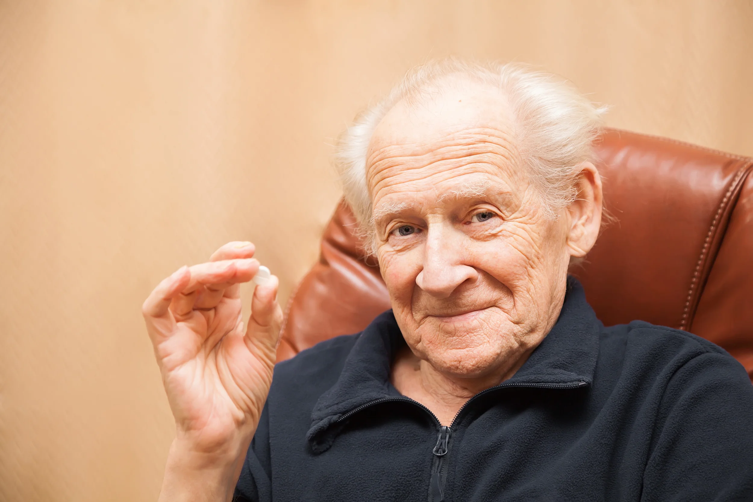 Elderly patient holding up pill