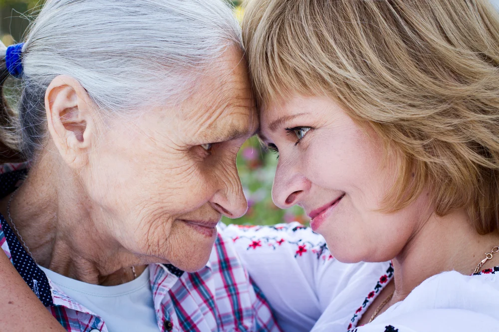 A daughter embracing her elderly Mother with Alzheimers.