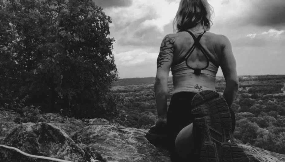 Megan Gouldner seated on a rock outcropping gazing over a vast landscape