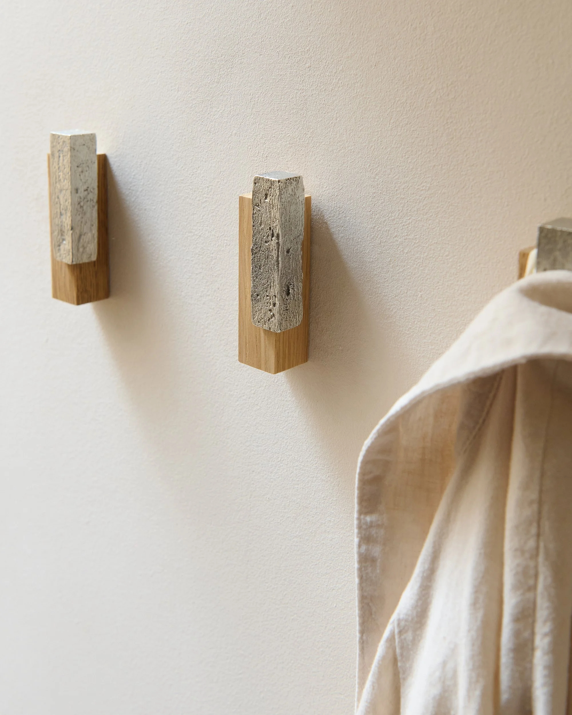 Sculptural oak and pewter wall hooks mounted on wall