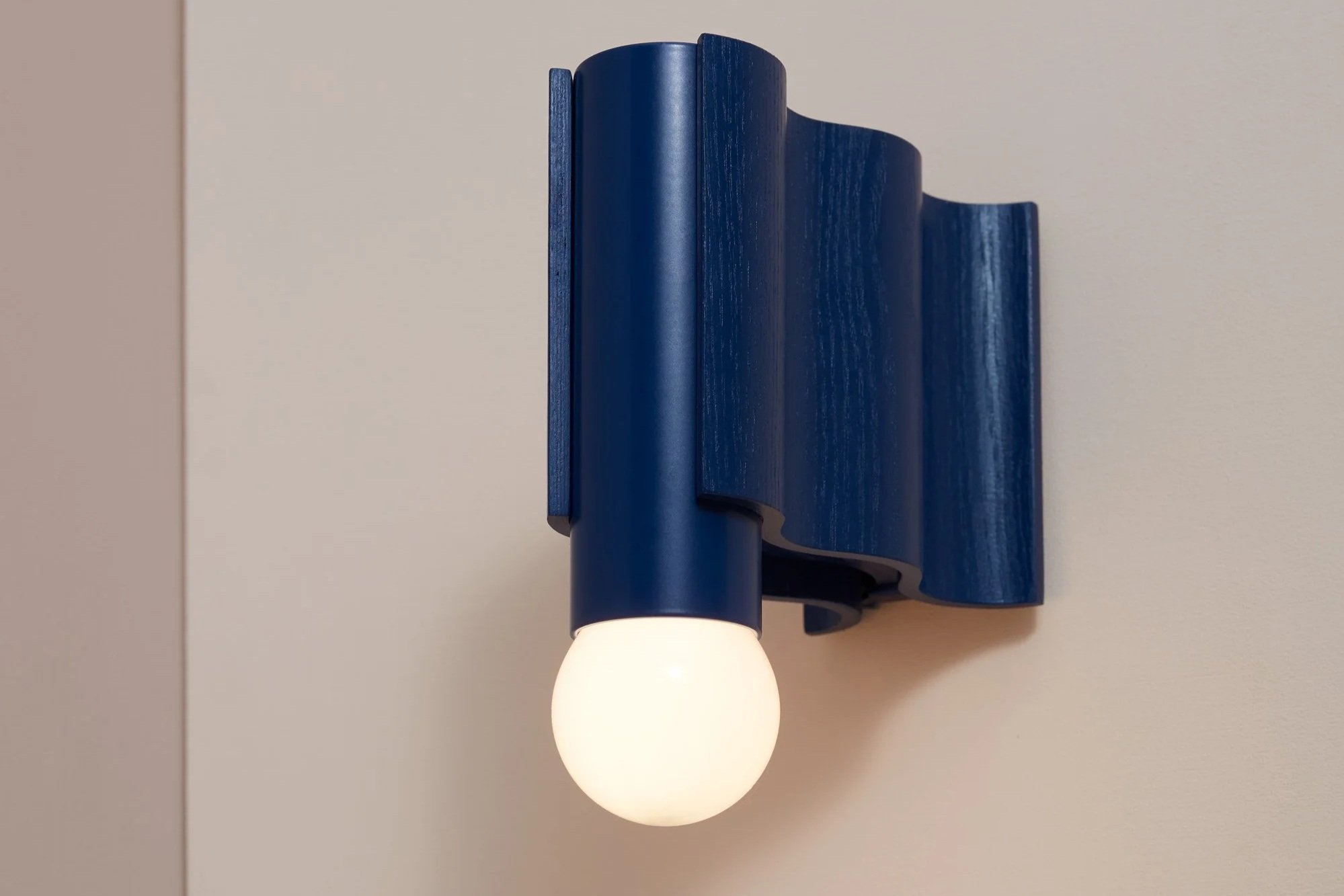 Blue Corrugation wall light made from veneer formed timber, aluminium and illuminated globe bulb