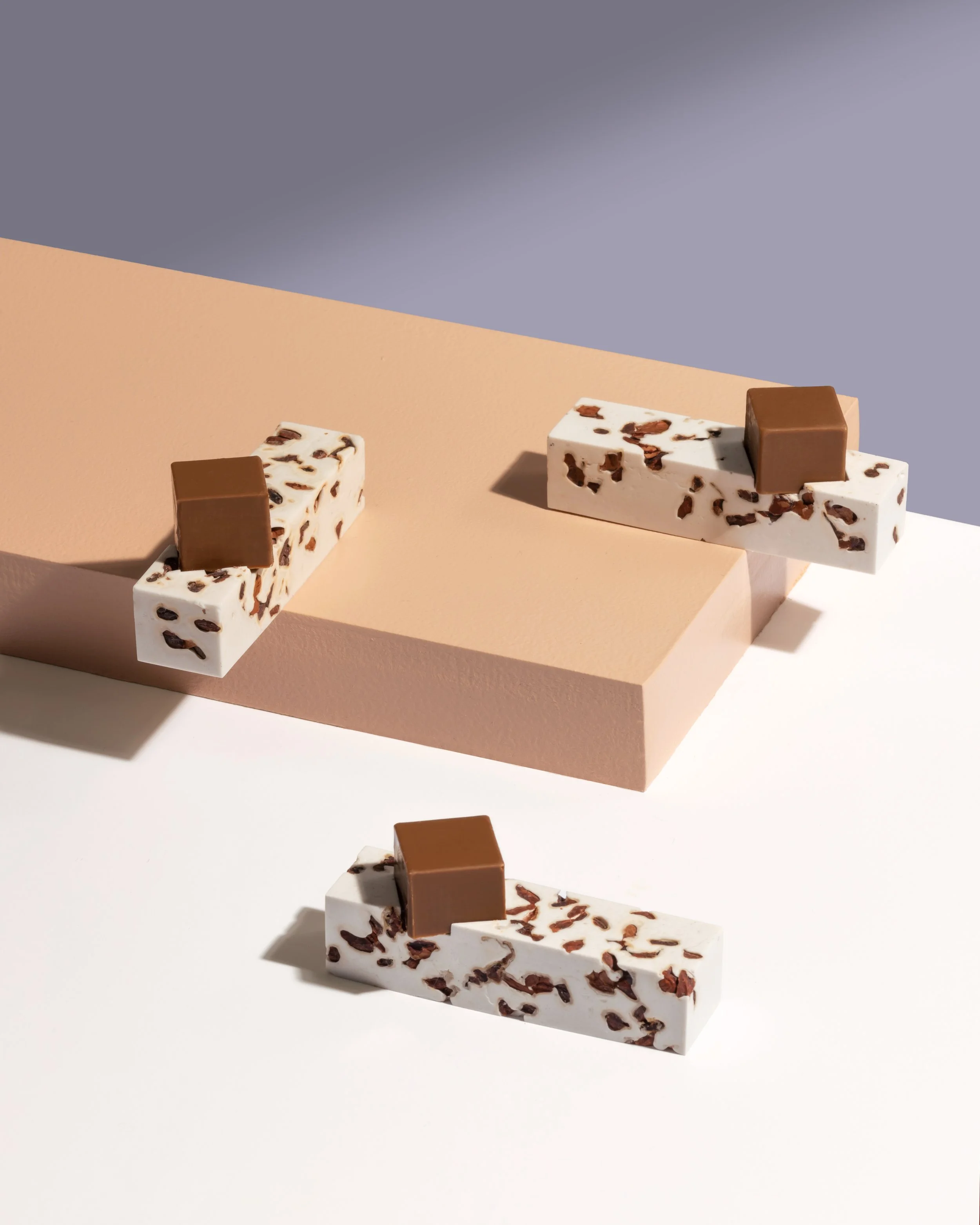 Chocolate tasting installation with sculptural confectionery pieces displayed on stepped geometric platforms for Omnom collaboration