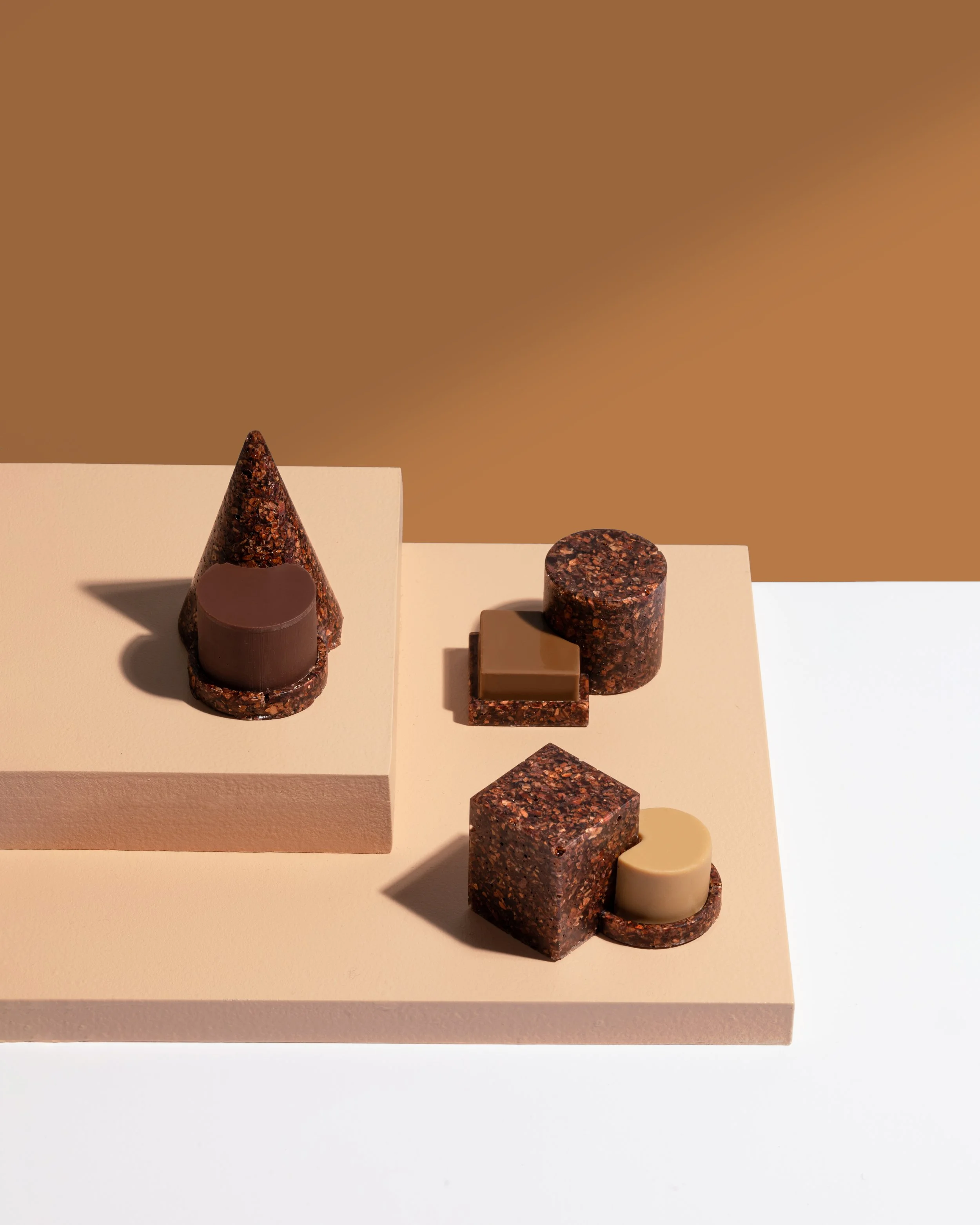 Minimal still life of sculptural chocolate forms arranged on geometric plinths in Omnom collaboration