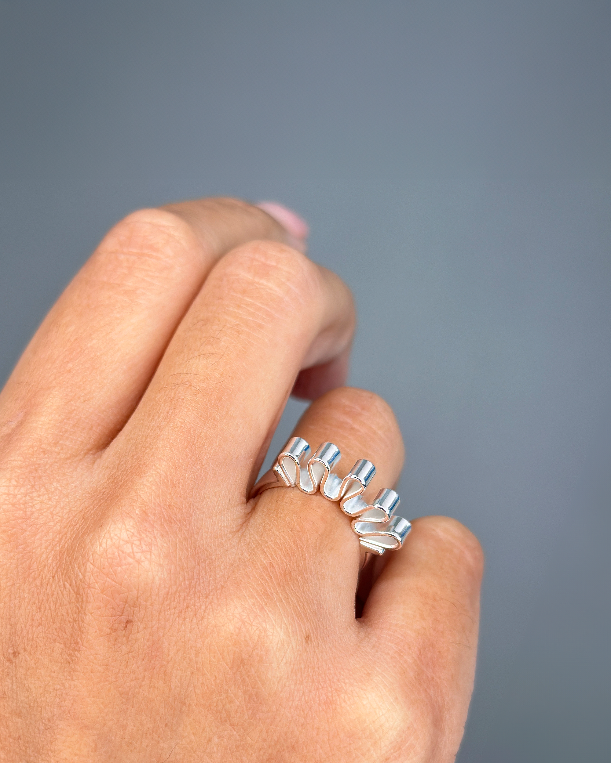 Model wearing Ribbon ring in silver and gold with folded sculptural detailing