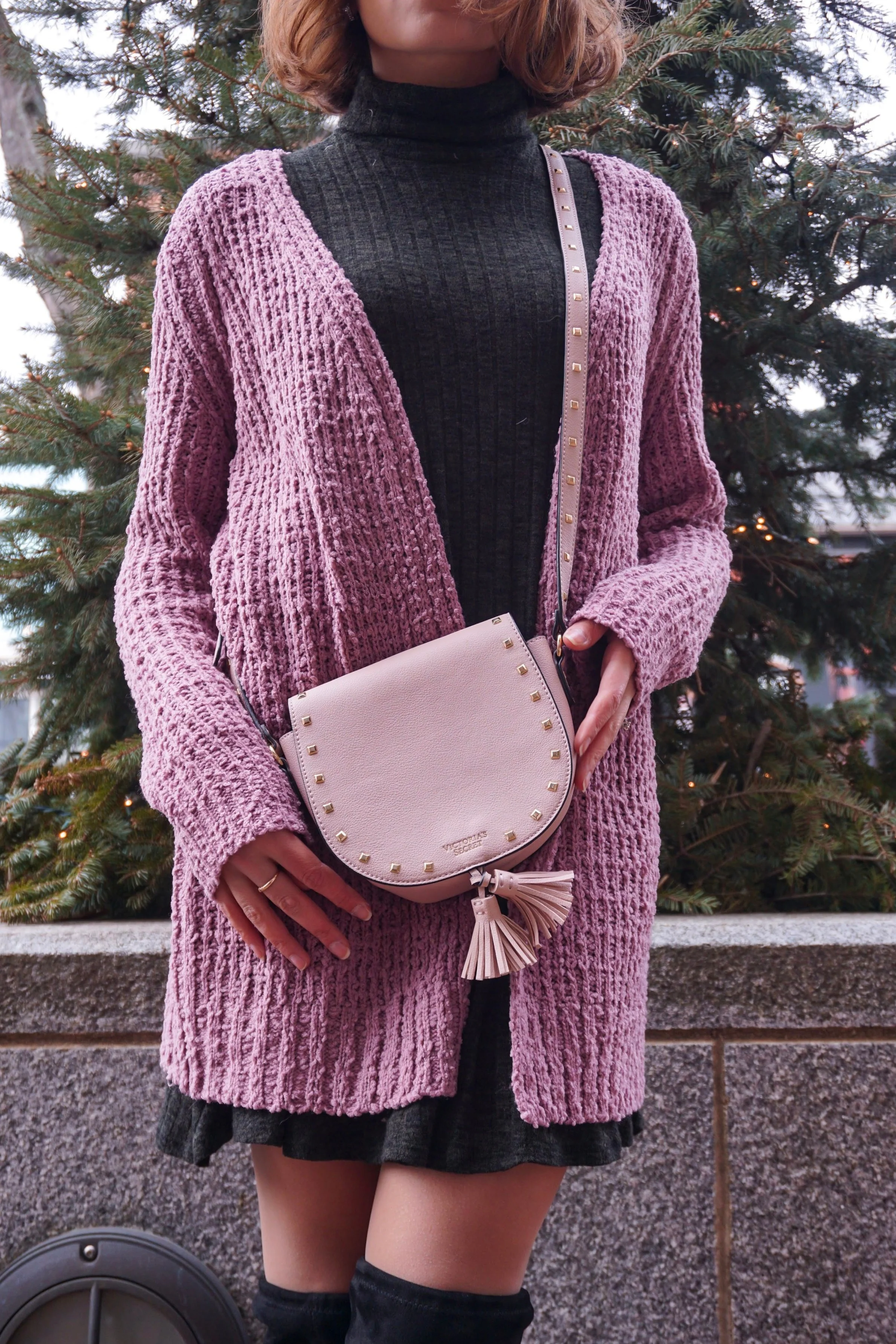 Blogger wearing a pink knit cardigan, green flare sweater dress, black high-knee boots, and pink Victoria Secret bag.
