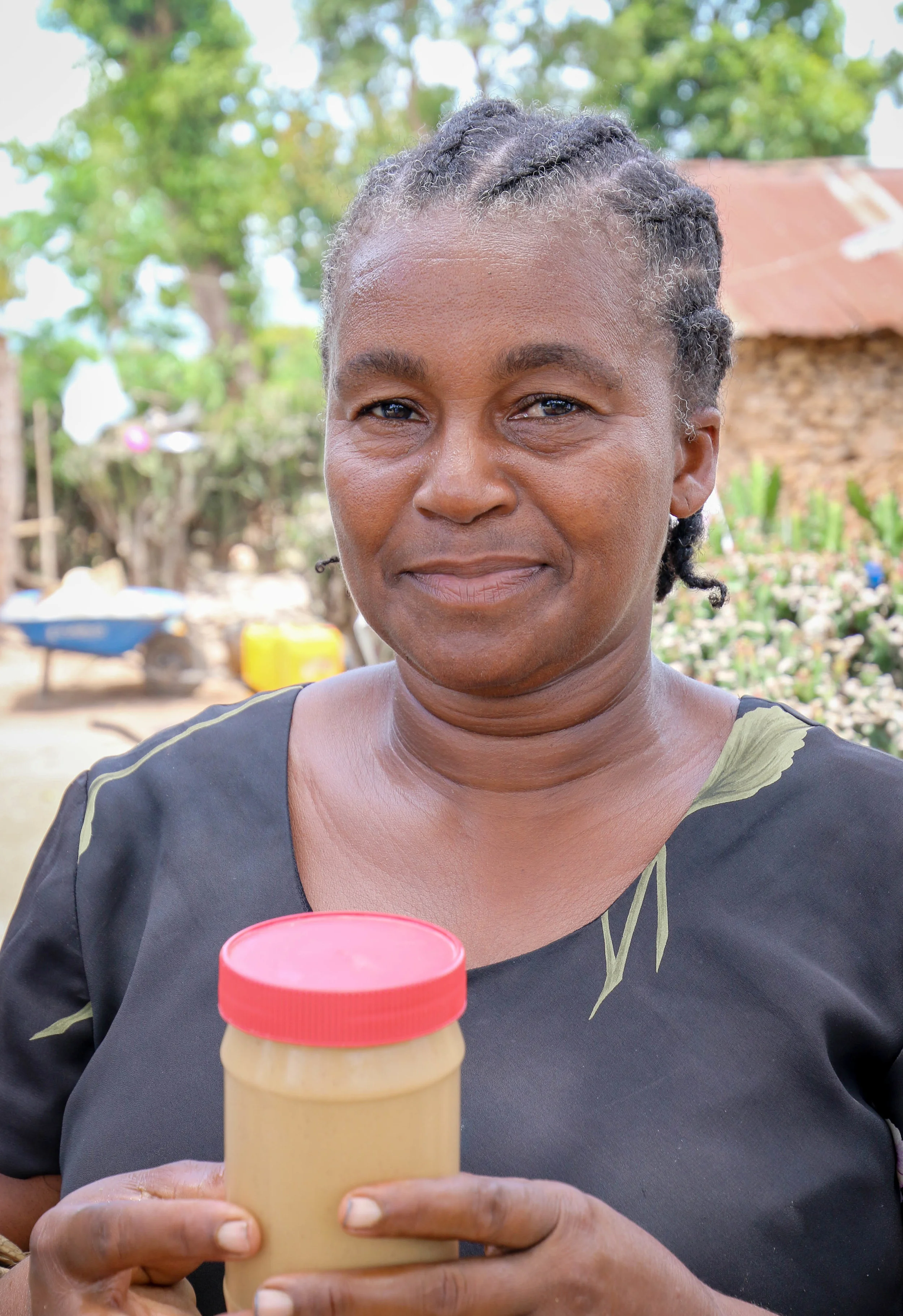 Estann Annyias, President of MCC supported peanut butter making co-op holding of jar of Haitian Mamba, peanut butter. Boyaha, Haiti.
