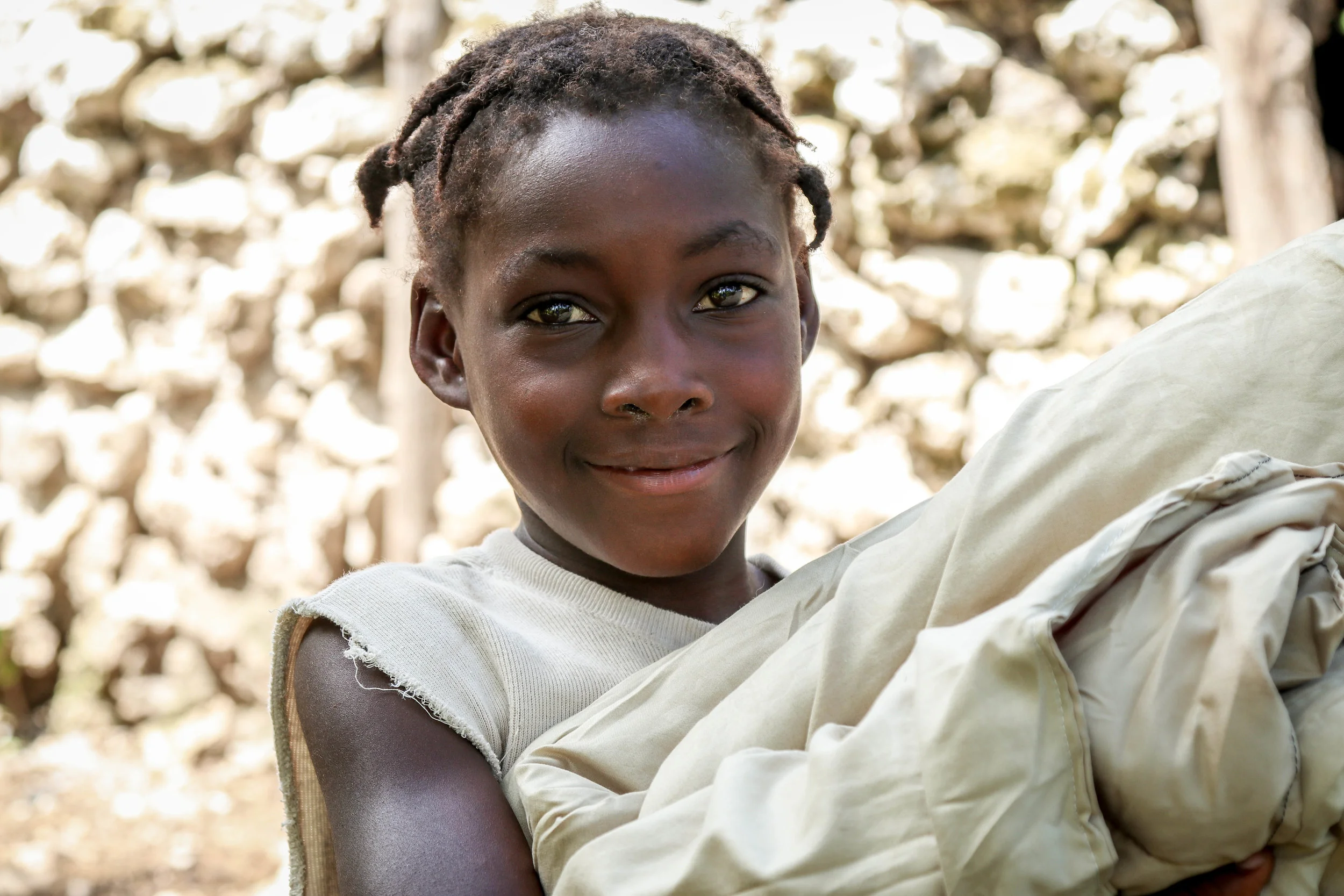 Fledana Mezi , 7 years old, holding an MCC relief blanket in the community of Biket.