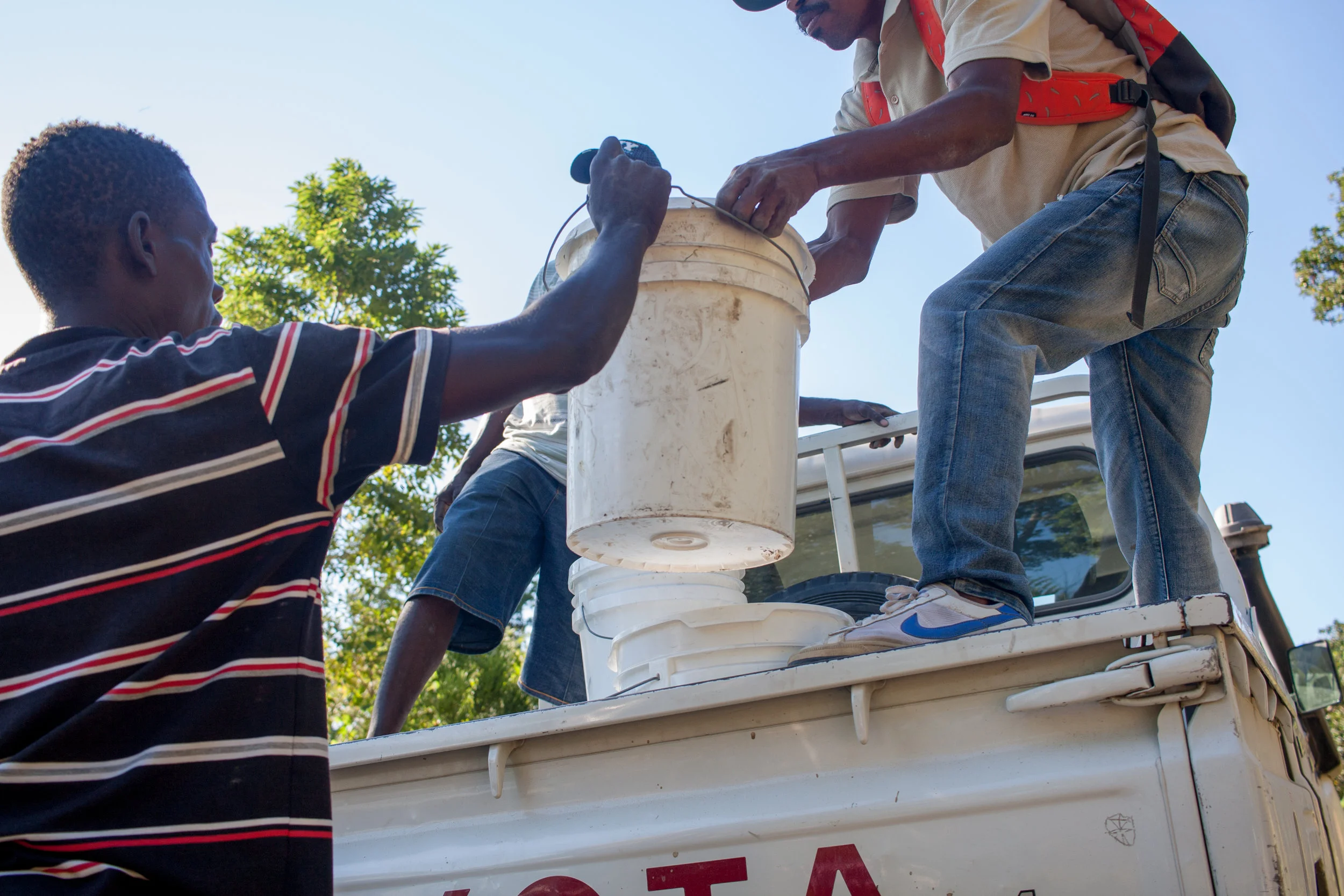 Residents of Bingo help unload relief buckets from the MCC pickup. MCC Photo/Annalee Giesbrecht