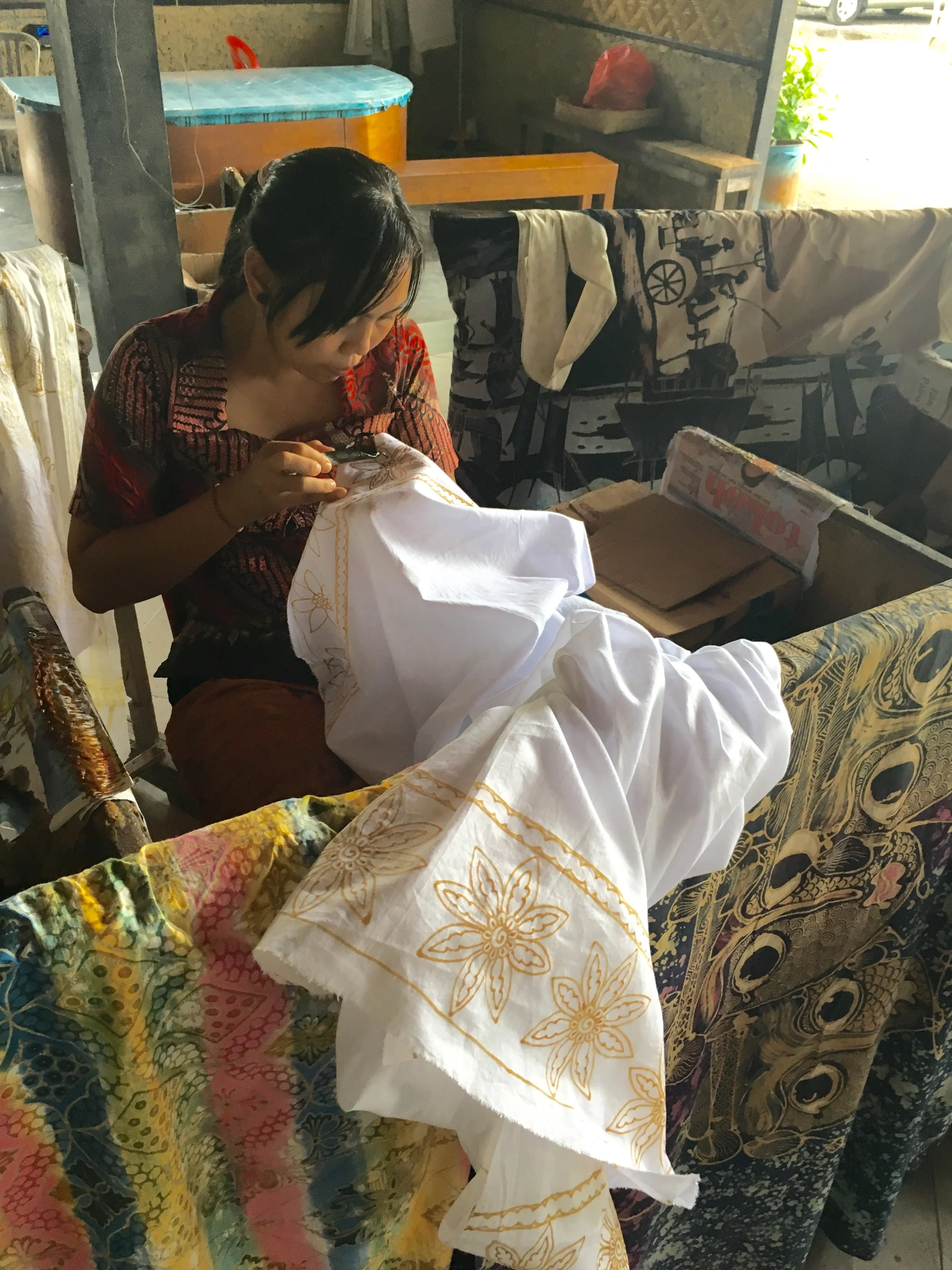 A Balinese woman drawing wax designs on fabric before she paints them.