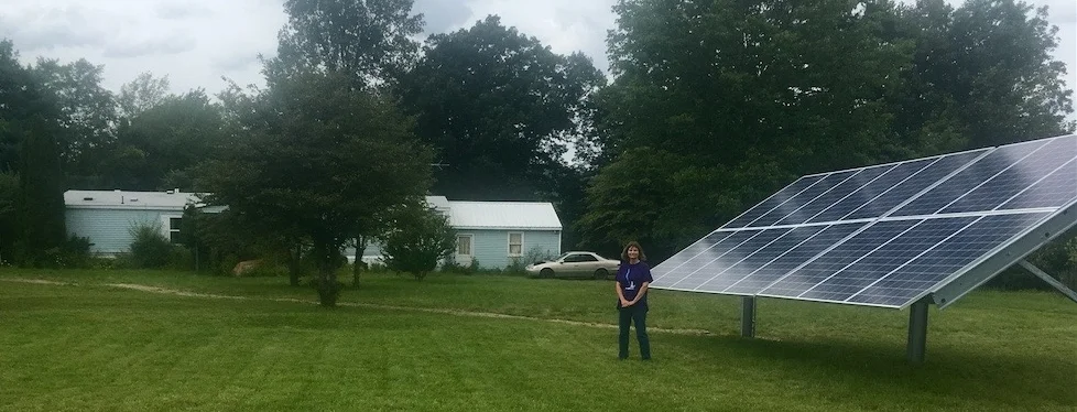 Gail with her ground-mounted solar system in front of her house.