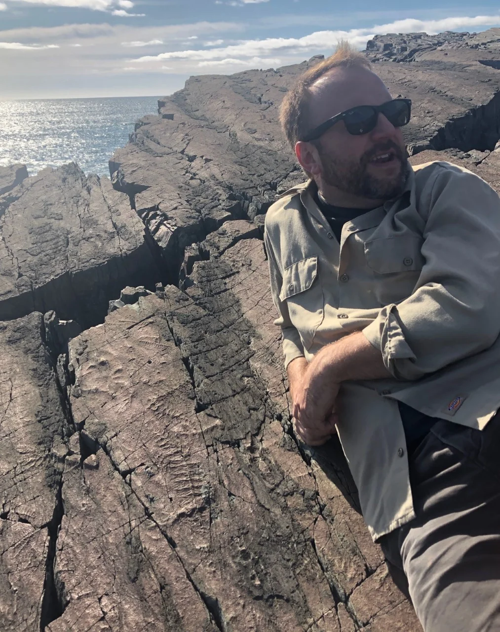 I’m relaxing on a 560 million year old cliff over the Atlantic Ocean at Mistaken Point Ecological Reserve, a UNESCO site. Next to me are fossils molds from some of the earliest known living organisms on our planet!