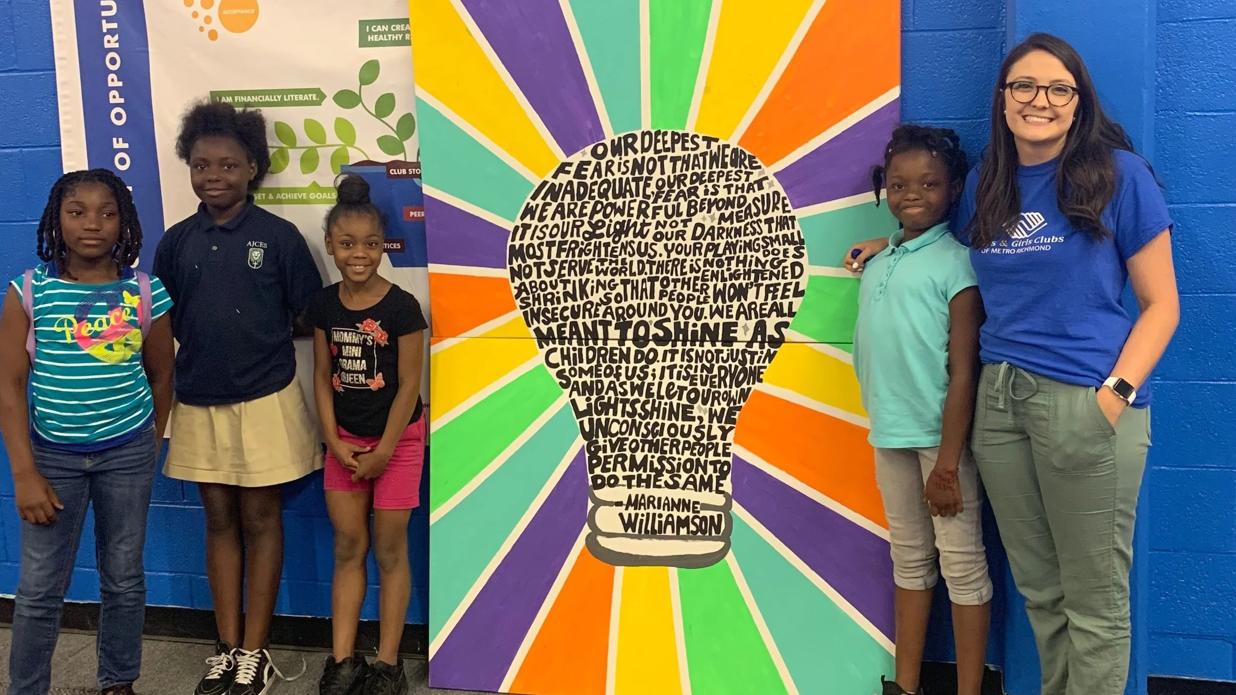 Members of the 1,000 Words interest club and Ms. Abby stand with their finished mural